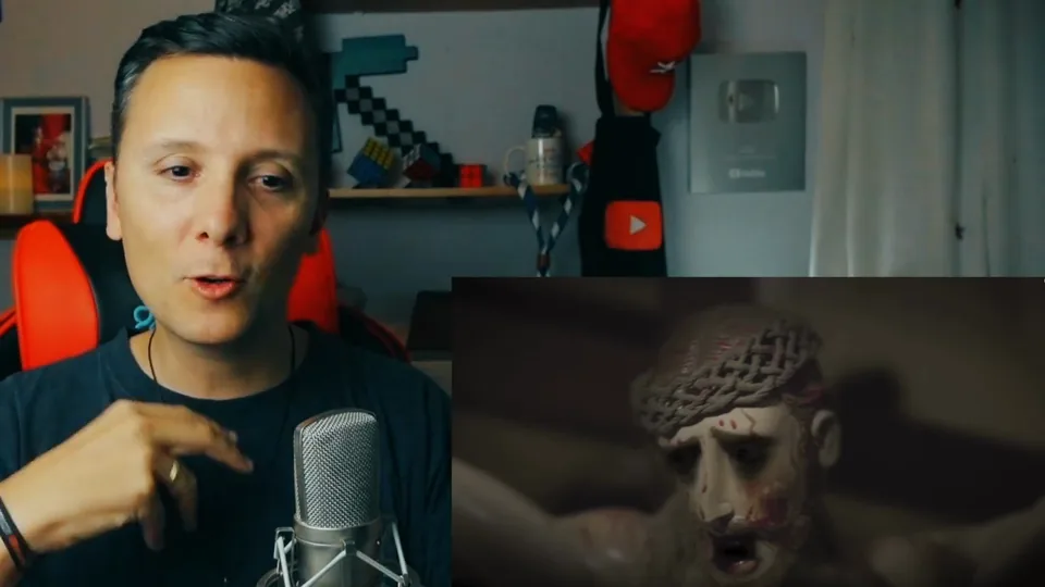 Daniel Pajuelo gesticula ante el micrófono; a su lado, un fragmento del vídeo de Dama G con una talla de Cristo coronado de espinas