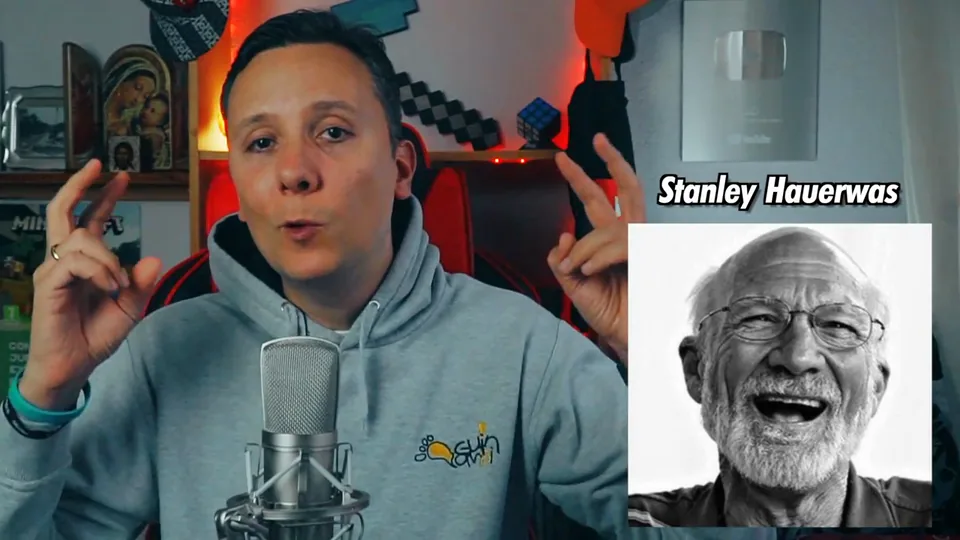 Daniel Pajuelo gesticula ante el micrófono junto a un retrato rotulado con el nombre de Stanley Hauerwas