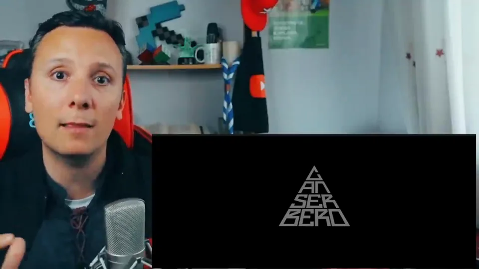 Daniel Pajuelo hablando a cámara junto a un recuadro negro con el logotipo triangular de Canserbero.