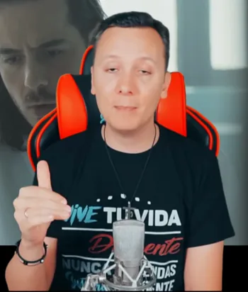 Daniel Pajuelo levanta una mano durante el comentario de Padre Nuestro, con parte del videoclip detrás.