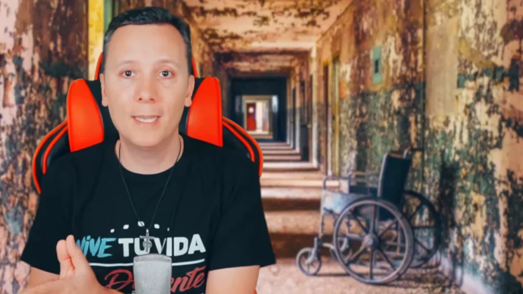 Daniel Pajuelo gesticula ante un fondo de pasillo y una silla de ruedas vacía.