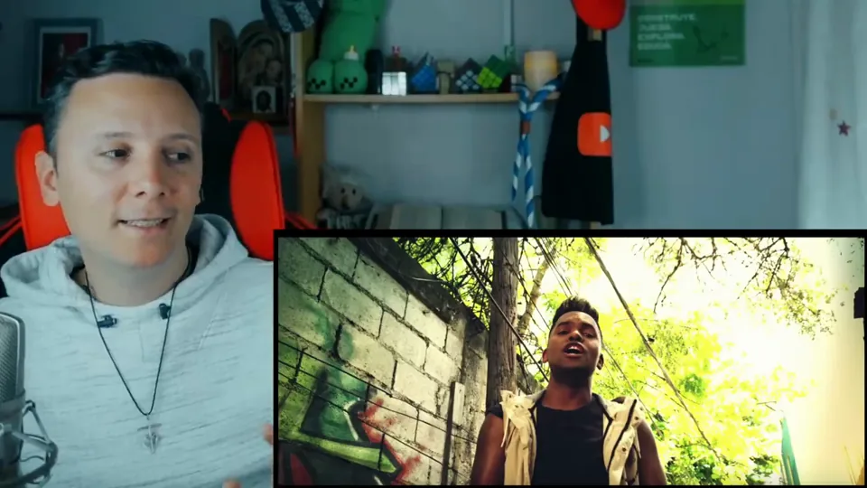 Daniel Pajuelo junto a un recuadro del videoclip Trapstorno con un intérprete junto a un muro.